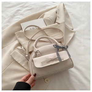Detail view of cream PU leather shell bag featuring elegant ribbon and plaid bow charm