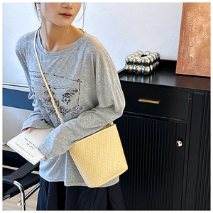 Detailed weave pattern on a beige bucket bag with an adjustable slim shoulder strap