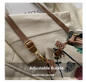 Detail of adjustable brown leather strap with gold buckle on woven bucket bag