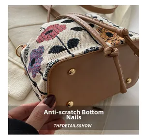 Detailed view of floral bucket bag base with protective gold metal bottom studs