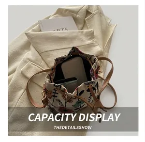Detail showing internal capacity of floral embroidery bucket bag with phone and wallet