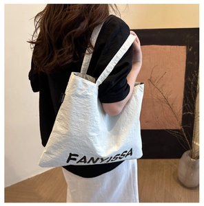 Model view showing the back carry of a white canvas tote bag with FANYISSA logo detail