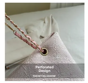 Detail of floral embroidery and gold metal grommet with chain strap on pink tote bag
