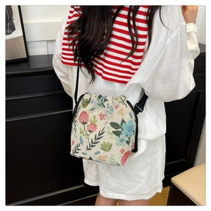 Detail of floral embroidery on a vintage cream bucket bag with drawstring closure