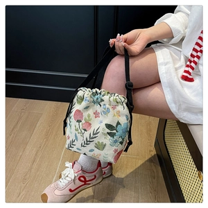 Detailed close-up of a floral jacquard drawstring bucket bag with elegant 3D flower accents