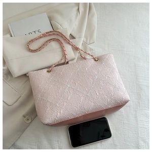 Detailed close-up of pink woven texture tote bag with golden chain and faux leather trim