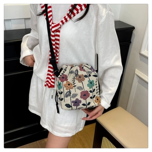 Detail of floral drawstring bucket bag with adjustable black strap on model