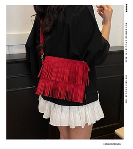 Modèle avec sac bandoulière rouge en daim à franges superposées et boucle métal doré