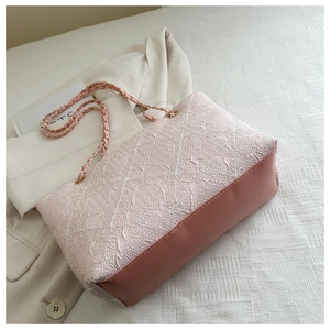 Detail of pink chain shoulder bag with white geometric woven texture and leather panels