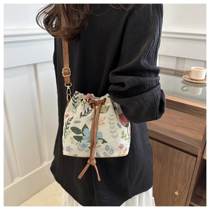 Dettaglio della borsa a secchiello jacquard floreale con coulisse in pelle marrone e metallo
