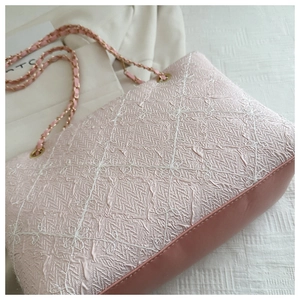 Detail of pink embroidered fabric tote bag with floral patterns and golden chain strap