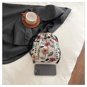 Detailed top view of floral canvas drawstring bucket bag with cord straps and mobile reference