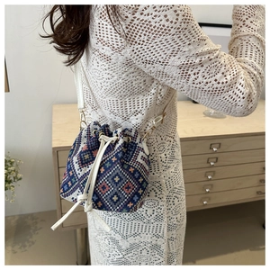 Dettaglio della borsa a secchiello intrecciata con coulisse bianca e motivi geometrici