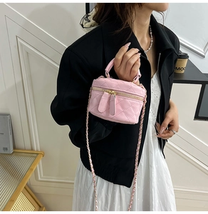Close-up of pink quilted mini vanity bag with golden chain strap and leather handle