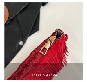 Detail showing high-quality gold metal zipper and red suede fringe on stylish bag