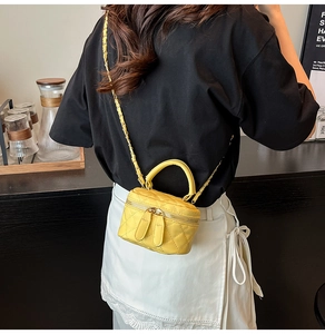 Detail der gelben gesteppten Mini-Box-Tasche mit goldener Kette an einem Model