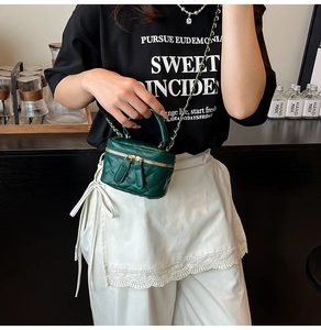 Detail of dark green quilted mini bag with gold chain strap and double zipper closure