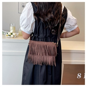 Macro view of a brown suede crossbody bag featuring long stylish fringes and metal clips