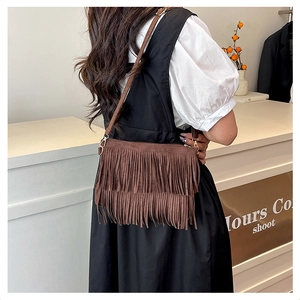 Détail du sac bandoulière en similicuir marron avec franges et boucles métalliques dorées