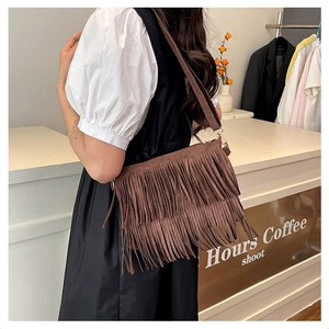 Détail d'un sac bandoulière bohème en daim marron avec franges et finitions en métal doré