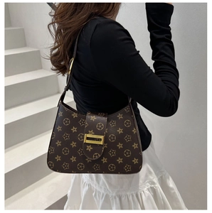 Dettaglio del motivo floreale vintage sulla borsa a spalla marrone con fibbia dorata