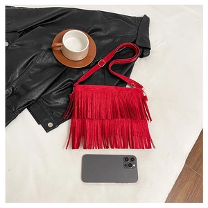 Detail view of red tassel crossbody bag with matte texture and size comparison to phone