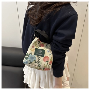 Detail of floral canvas tote bag featuring a green label shown on a model in daily outfit
