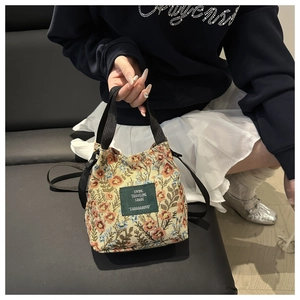Detailed macro view of retro floral jacquard canvas bucket bag with green woven label