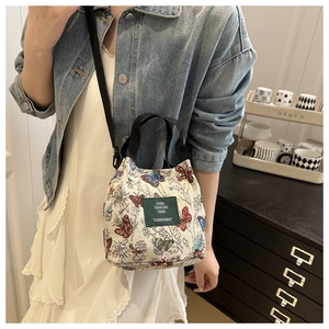 Detail of floral butterfly embroidery on canvas bucket bag with adjustable shoulder strap