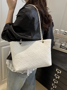 Fashionable white tweed tote bag with gold chain strap shown on model in a modern room