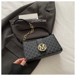 Detail of golden M-logo clasp and monogram leather pattern on a black shoulder bag