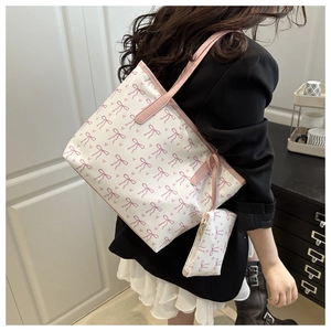 Model wearing large white tote bag with pink bow pattern and matching small pouch