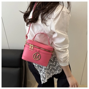 Detail showing pink leather mini box bag with golden M logo and metallic dual zippers