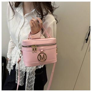 Close-up of pink box bag featuring a golden M logo and metallic zipper details