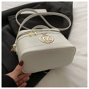 Dettaglio della borsa a scatola bianca con logo M dorato e finiture metalliche su un blazer