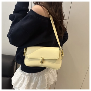 Close-up of a pale yellow leather shoulder bag featuring a gold metal buckle clasp