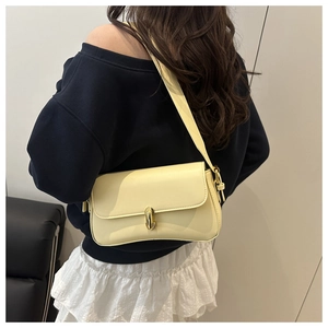 Vue arrière d'un mannequin portant un sac sous le bras en cuir jaune clair à boucle dorée
