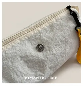 Détail d'une trousse de maquillage en nylon blanc avec tissu texturé et logo M FASHION