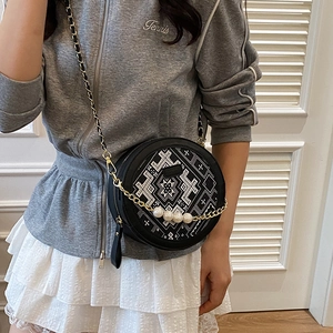 Chic black round crossbody bag with white embroidery and pearl-accented gold chain strap