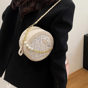 Elegant off-white round crossbody bag with floral embroidery and pearl chain strap