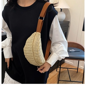 Detail of woven straw crossbody bag with brown nylon strap and silver metal buckle adjustment