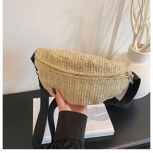 Detail of woven straw crescent chest bag with black adjustable strap and silver zipper closure