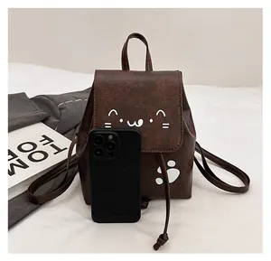 Mini brown cat backpack detail showing compact size compared to a smartphone