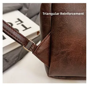 Detail of reinforced triangle stitching and golden D-ring on brown leather backpack