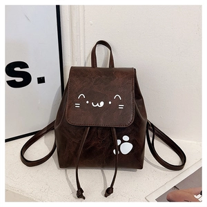 Detail of dark brown mini backpack featuring a cute white cat face and paw print design