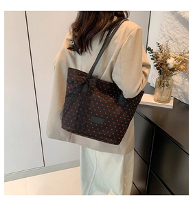 Détail d'un grand sac cabas noir à motifs cœurs rouges avec un nœud en dentelle chic