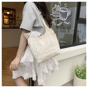 Detailed close-up of cream lace tote bag featuring floral patterns and side bow tie