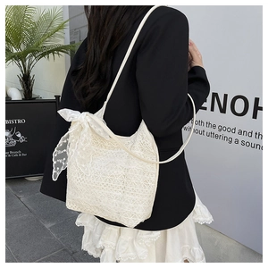 Close-up of white crochet lace tote bag with large decorative bow on model's shoulder