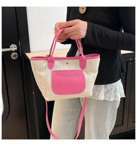 Detail der Strohtasche mit Fischgrätmuster, rosa Lederbesatz und praktischen Tragegriffen