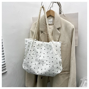 Detail of white tote bag featuring black bow patterns and textured seersucker fabric